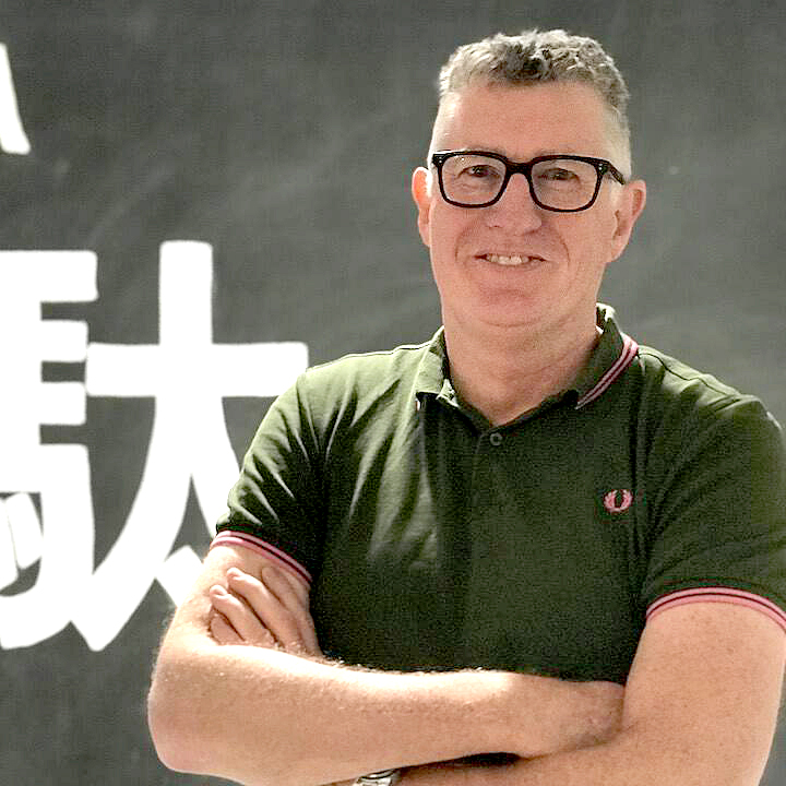 Nigel Dalton standing in front of Japanese characters for muda or waste Nigel Dalton Thoughtworks social scientist lean agile